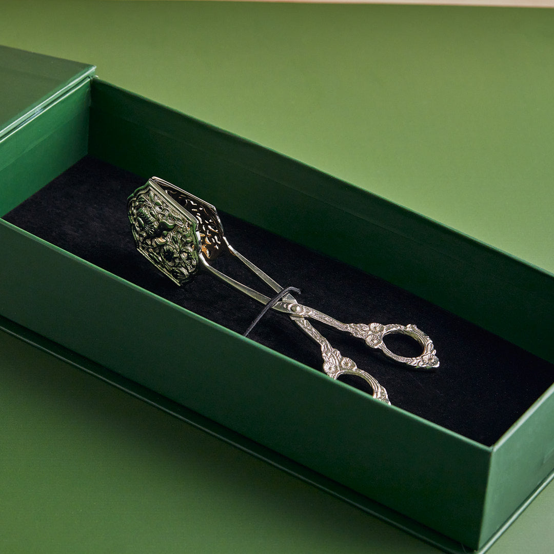 Decorative silver scissors in a green box with black interior